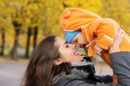 Mother and her toddler son playing in the park. Autumn nature background. Love and family concept.の写真素材