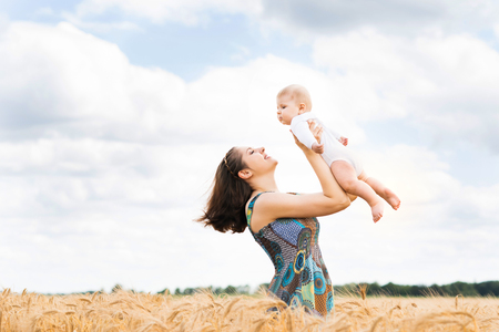 Young and beautiful woman playing with her infant baby in a meadow of wheat. Summer concept.の写真素材