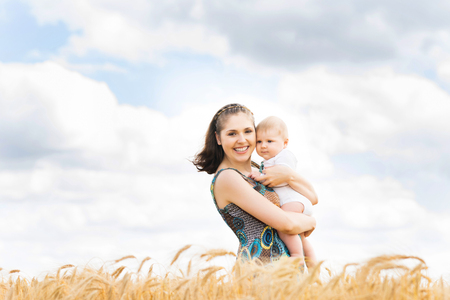 Young and beautiful woman playing with her infant baby in a meadow of wheat. Summer concept.の写真素材