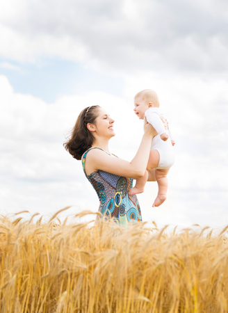 Young and beautiful woman playing with her infant baby in a meadow of wheat. Summer concept.の写真素材