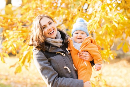 Mother and her toddler son playing in the park. Autumn nature background. Love and family concept.の写真素材