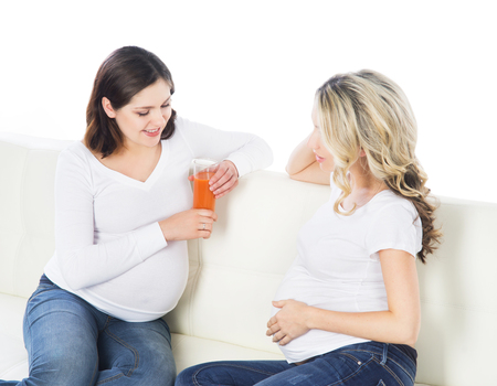 Two expectant mothers staying healthy with fruits and fresh juice.の写真素材