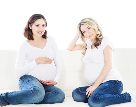 Two attractive expectant mothers chatting with each other.の写真素材