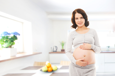 Woman expecting a baby. Pregnant girl at home. Kitchen with window.の写真素材