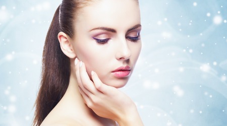 Portrait of young, beautiful and healthy woman: over winter background. Healthcare, spa, makeup and face lifting concept.の写真素材