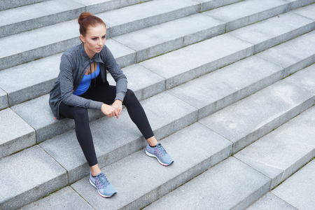 Young, fit and sporty woman resting after the training. Fitness, sport, urban jogging and healthy lifestyle concept.の写真素材