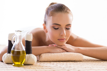 Young, beautiful and healthy woman relaxing in spa salon. Traditional oriental aroma therapy and massaging treatmentsの写真素材
