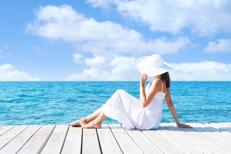 Beautiful, attractive model posing in white dress on a wooden piの写真素材