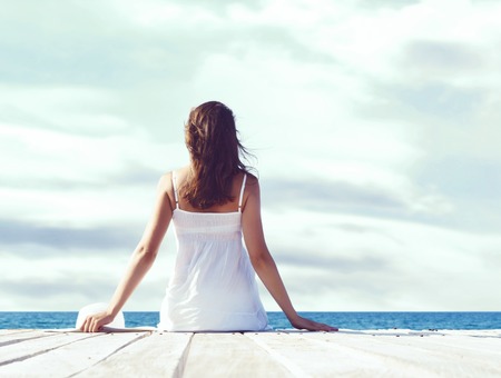 Beautiful, attractive model posing in white dress on a wooden piの写真素材