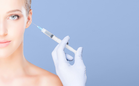 Doctor injecting in a beautiful face of a young woman.の写真素材