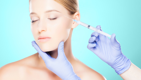 Doctor injecting in a beautiful face of a young woman.の写真素材