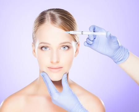 Doctor injecting in a beautiful face of a young woman.の写真素材