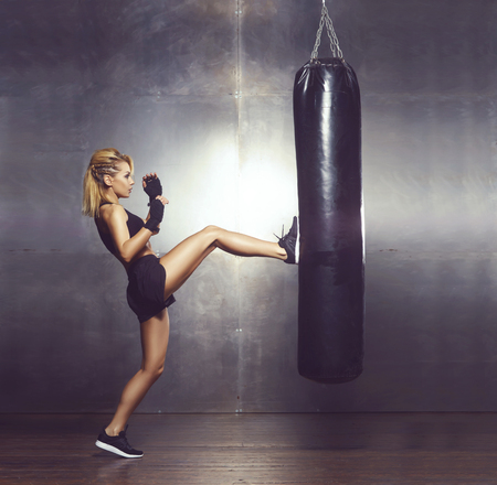 Fit and sporty young girl having a kickboxing training. Underground gym. Health, sport, fitness concept.の写真素材