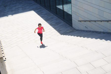 Young, fit and sporty woman running up the stairs. Fitness, sport, urban jogging and healthy lifestyle concept.の写真素材