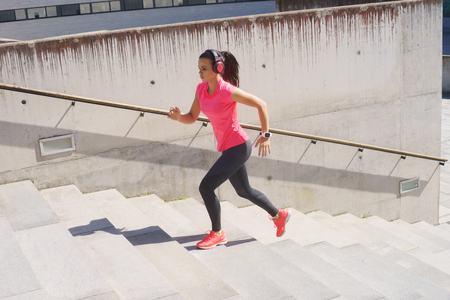 Young, fit and sporty woman running up the stairs. Fitness, sport, urban jogging and healthy lifestyle concept.の写真素材