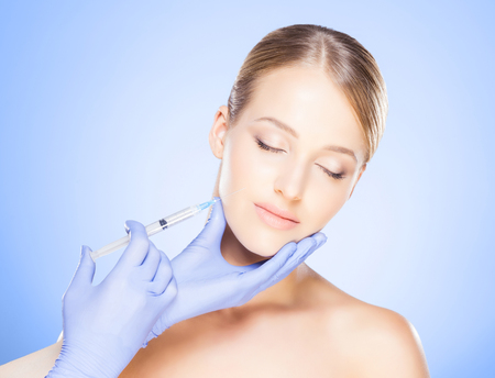 Doctor injecting in a beautiful face of a young woman. Plastic sの写真素材