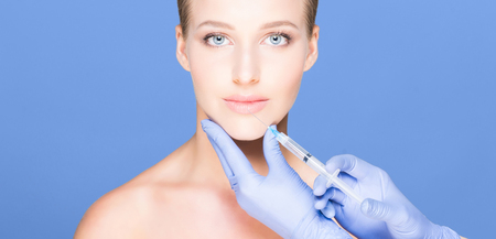 Doctor injecting in a beautiful face of a young woman. Plastic sの写真素材
