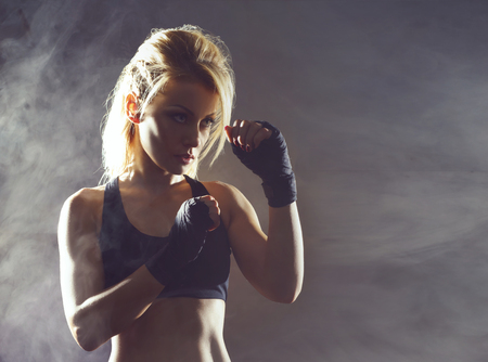 Fit and sporty young girl getting ready for a kickboxing training. Underground gym. Health, sport, fitness concept.の写真素材