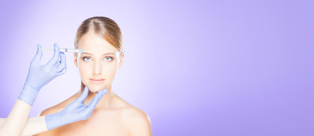 Doctor injecting in a beautiful female face. Plastic surgery concept.の写真素材