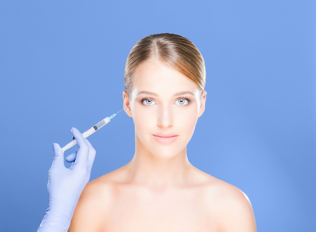 Young, beautiful and healthy woman having skin injections over magenta background.の写真素材