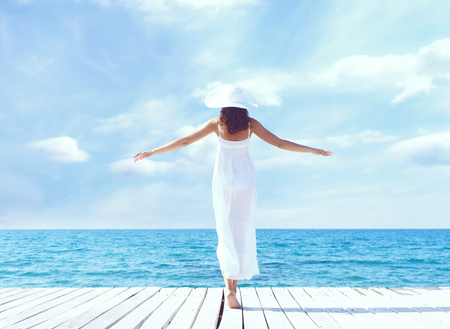 View from the back of beautiful and healthy girl on wooden pier. Vacation, resort and traveling.の写真素材