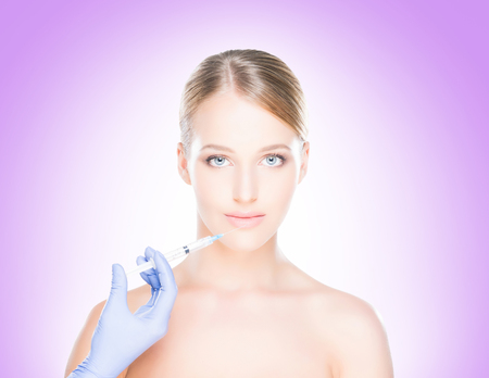 Young, beautiful and healthy woman having skin injections over magenta background.の写真素材