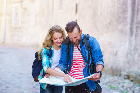 Young travelers with a tourist map. Man and woman having vacation. Backpackers, traveling and tourism concept.の写真素材