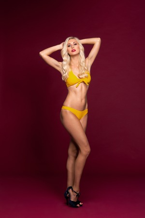 Young and beautiful woman in swimsuit over red background.の写真素材