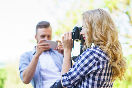 Man and woman taking photos with a camera and a smartphone.の写真素材