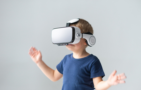 Portrait of happy boy in a virtual reality headset. Attractive kid using vr goggles at home. Entertainment technology and generation Z concept.の写真素材
