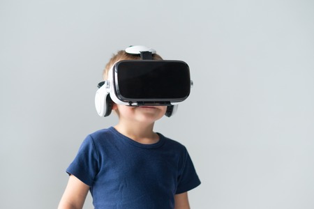 Portrait of happy boy in a virtual reality headset. Attractive kid using vr goggles at home. Entertainment technology and generation Z concept.の写真素材