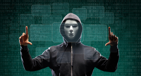 Computer hacker in mask and hoodie over abstract binary background. Obscured dark face. Data thief, internet fraud, darknet and cyber security.の写真素材