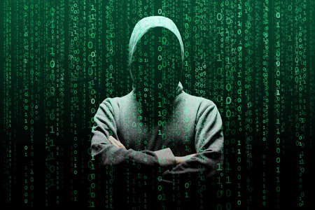 Computer hacker in mask and hoodie over abstract binary background. Obscured dark face. Data thief, internet fraud, darknet and cyber security.の写真素材