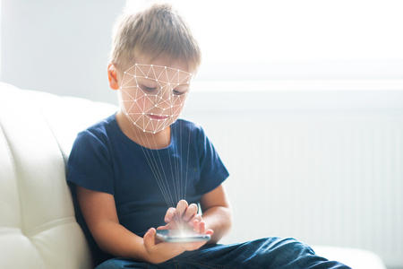 Little boy using face id authentication. Kid with a smartphone. Digital native children concept.の写真素材