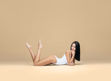 Attractive and sporty woman posing in white swimsuit. Fit and athletic body. Beautiful girl in swimsuit. Fitness, diet and weight loss concept.の写真素材