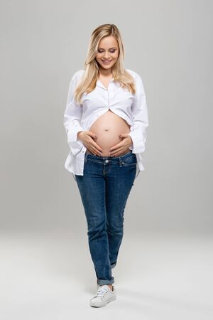 Young pregnant woman in studio. Beautiful stomach. Pregnancy, childbearding and new life concept.の写真素材