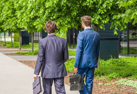Confident business men talking in front of modern office building. Businessman and his colleague. Banking and financial market.の写真素材