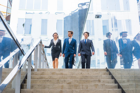 Confident businesspersons talking in front of modern office building. Businessmen and businesswoman...