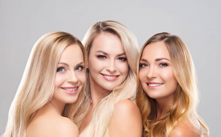 Studio portrait of young, beautiful and natural blond women over grey background. Close-up of smiling girls. Face lifting, plastic surgery, cosmetics and make-up.の写真素材