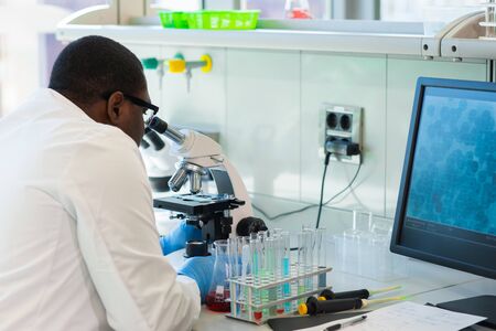 African-american medical doctor working in research lab. Science assistant making pharmaceutical experiments. Chemistry, medicine, biochemistry, biotechnology and healthcare concept.の写真素材