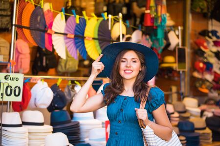 Young and beautiful brunette girl in dress and hat walking outdoor at the market. Nice, France. Summer vacation, traveling and tourism.の写真素材