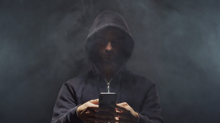 Portrait of computer hacker in hoodie. Obscured dark face. Data thief, internet fraud, darknet and...