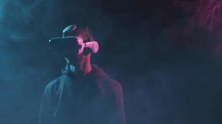 Portrait of a man in virtual reality helmet. Obscured dark face in VR goggles. Internet, darknet, gaming and cyber simulation.の写真素材