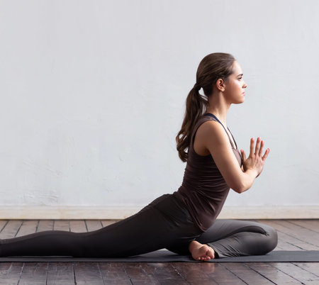 Young and fit woman practicing yoga indoor in the class. Stretching exercise in the day light....