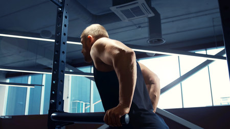 Athletic handsome male sportsman working in the gym using barbell. Strong and healthy bodybuilder...
