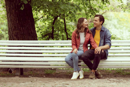 Young, happy, loving couple having date on the bench in the park. Relations, friendship and love.の写真素材