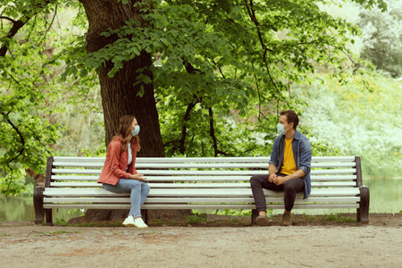 Young, happy, loving couple having date in the park during the coronavirus lockdown crisis....