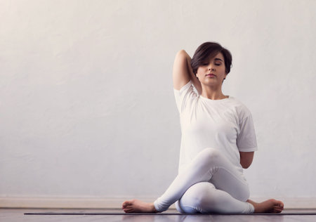 Young and fit woman practicing yoga indoor in the class. Stretching exercise in the day light....