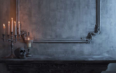 Mystical Halloween still-life background. Skull, candlestick with candles, old fireplace. Horror and witchery concepts.の写真素材