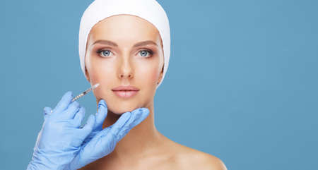 Doctor injecting in a beautiful face of a young woman. Plastic surgery concept.の写真素材